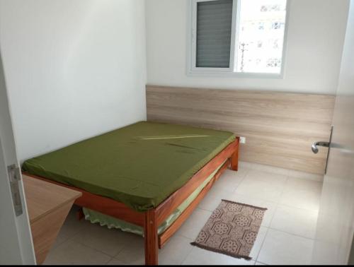a room with a bed with a green sheet on it at Villa Monrealle Praia Itaguá in Ubatuba