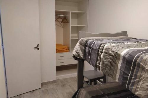 ein Schlafzimmer mit einem Bett und einem Stuhl neben einem Schrank in der Unterkunft Departamentos Calasanz PB 4 in Mar del Plata