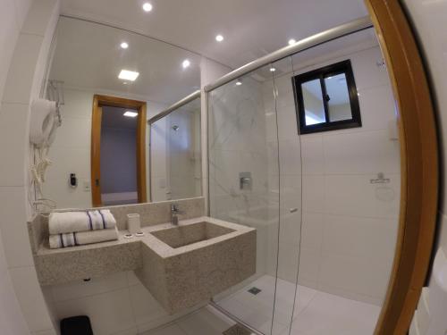 a bathroom with a sink and a glass shower at Flat Apart Hotel Crystal Place in Goiânia