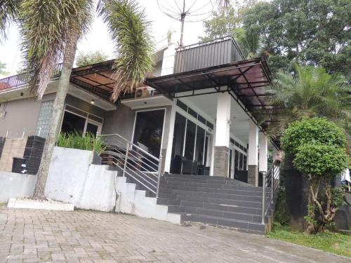 a house with stairs and a porch with palm trees at Oase Van Java in Salatiga