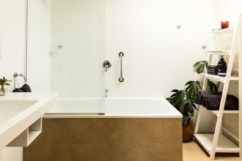 Baño blanco con bañera y lavamanos en Daisy Bank Cottages, en Richmond
