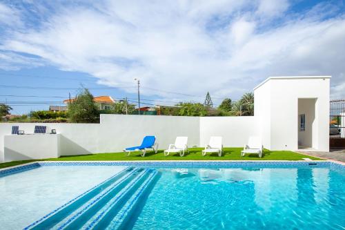 a swimming pool with two chairs and a house at Genesis Apartments Jan Thiel in Willemstad