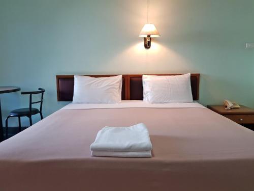 Una cama blanca grande con una toalla blanca. en Boonthavon, en Chiang Mai