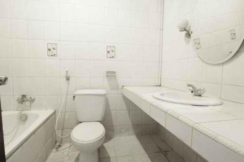 a white bathroom with a toilet and a sink at De'Qur Hotel Bandung in Bandung