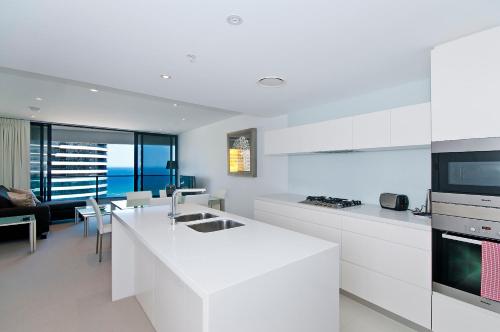 a kitchen with white appliances and a living room at Oracle Resort Broadbeach - gclr in Gold Coast