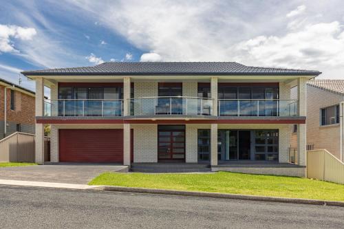 a large house with a balcony on a street at Burgess Beach 1 in Forster