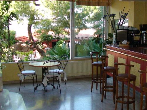 a patio with a table and chairs and a window at Hôtel Alexandra in Roquebrune-Cap-Martin