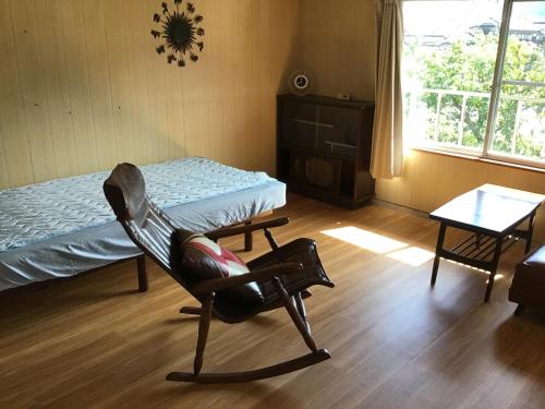 a bedroom with a chair and a bed and a table at 富乃亭 in Maniwa