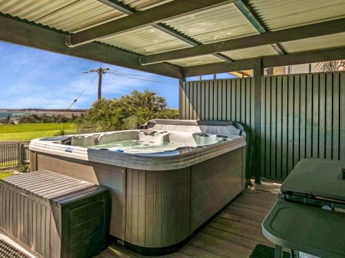 a large hot tub sitting on a deck with a bench at Gokus Shack Rural and water views with a spa in Corinella