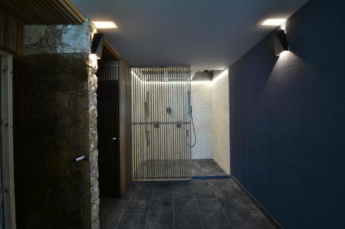 a hallway with a shower in a room with a blue wall at Boutique Hotel by BlackSeaRama in Balchik