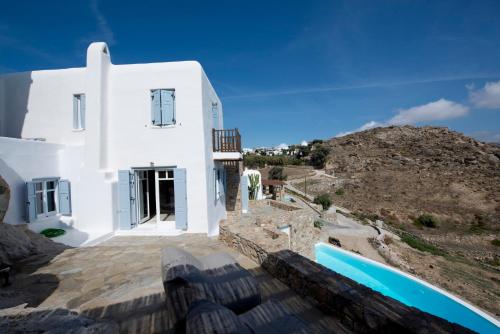 a white house with a hill in the background at Villa Azurite with heated pool by Diles Villas in Psarou