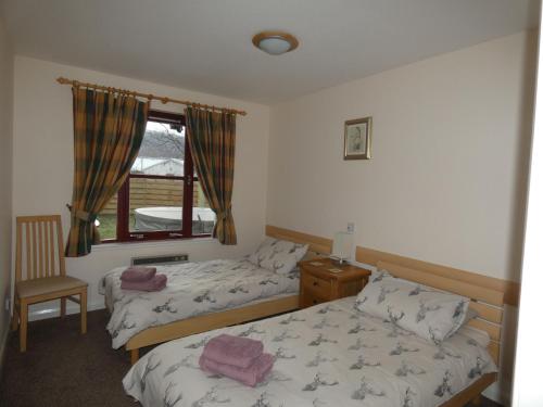 a bedroom with two beds and a window at Appin Lodge in Aviemore