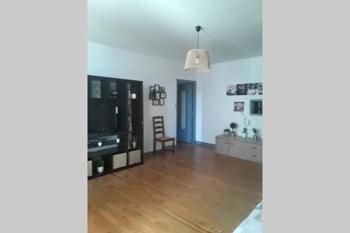a living room with a wooden floor and a tv at Appartement chaleureux de 82M2 proche de Vulcania in Pontaumur