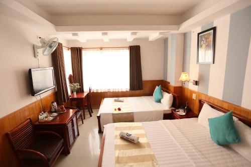 Habitación de hotel con 2 camas y TV en New Day Hotel, en Nha Trang