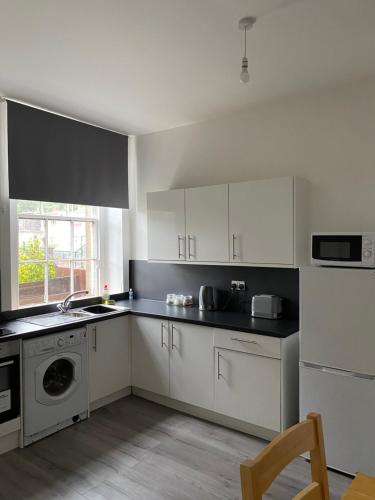 a kitchen with white cabinets and a sink and a dishwasher at Union Street Apartment in Hawick