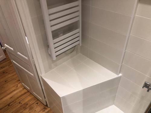 - une étagère blanche dans une salle de bains pourvue d'un radiateur dans l'établissement DU MANN petite maison jardin à 100m du port de Vannes avec PARKING, à Vannes