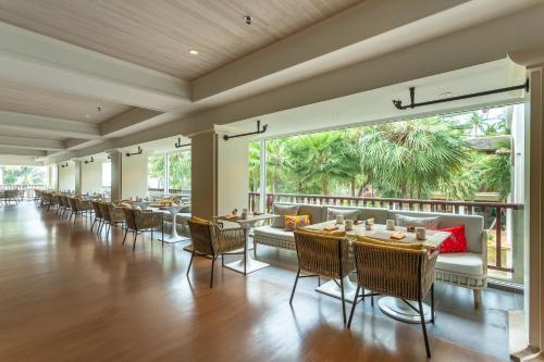 a dining room with tables and chairs and large windows at JW Marriott Phuket Resort and Spa in Mai Khao Beach