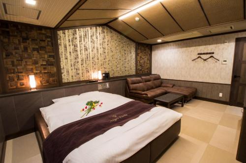 a bedroom with a large bed and a chair at ホテル アンジュエトワール 堺 - Adult Only in Sakai