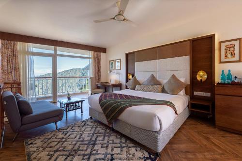 - une chambre avec un grand lit et une grande fenêtre dans l'établissement juSTa Mukteshwar Retreat & Spa, à Mukteswar
