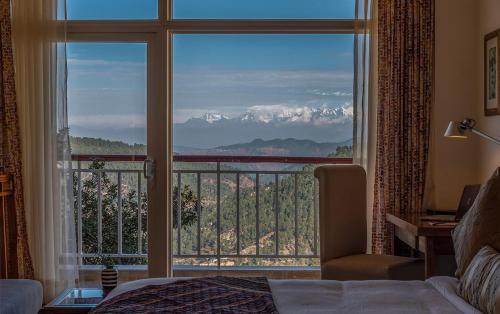 a room with a large window with a view at juSTa Mukteshwar Retreat & Spa in Mukteswar
