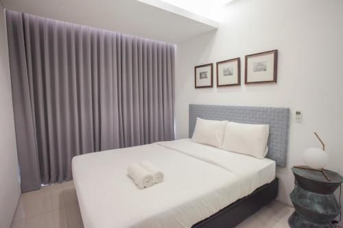 a bedroom with a white bed and a window at Premium 2BR Apartment near Marvell City Mall at The Linden By Travelio in Surabaya