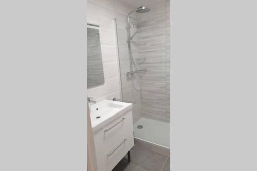une salle de bain avec un lavabo blanc et une douche dans l'établissement Appartement 50 m2, Calme, Marche à pied, Proche mer, à Guidel