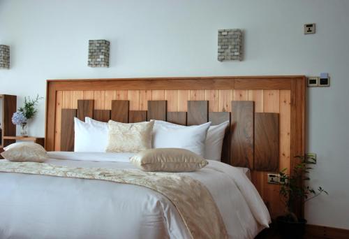 a bedroom with a white bed with a wooden headboard at Cottage San Francesco in Nuwara Eliya