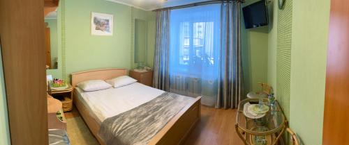 a small bedroom with a bed and a window at Hotel Khozyayushka in Perm