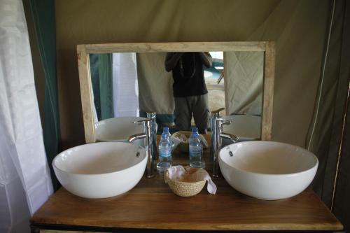 a person taking a picture of a bathroom with two sinks at Osero Serengeti Luxury Tented Camp in Banagi