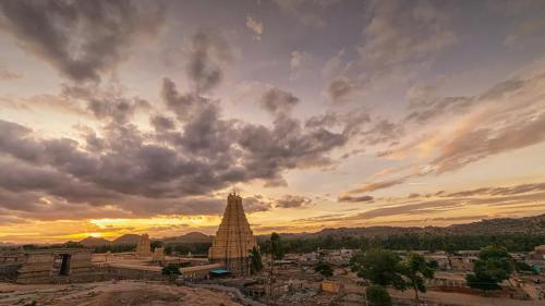 a sunset over a city with a large clock tower at Mango Tree Homestay in Hampi