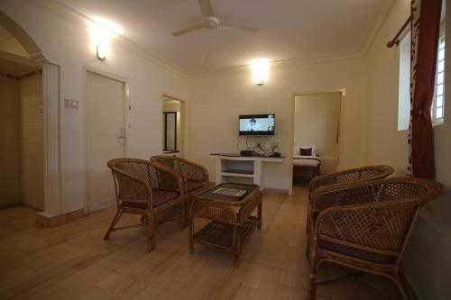 sala de estar con sillas, mesa y TV en Cliffhanger Retreat, en Yercaud