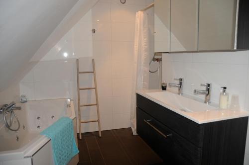 ein Badezimmer mit einem Waschbecken und einer Badewanne in der Unterkunft 't Geheim van de Molenaer in Kampen