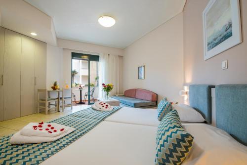 スタロスにあるクレタ パーム リゾート ホテル＆アパートメントのベッドとリビングルームが備わるホテルルームです。