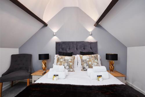 a bedroom with a large white bed with two chairs at The Wood Loft in Kegworth