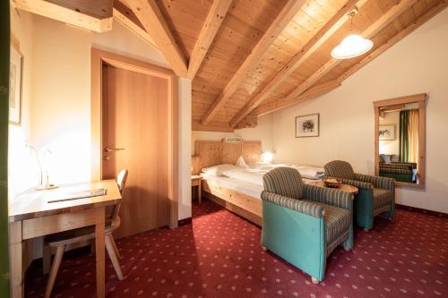 a hotel room with a bed and a desk and chairs at Hotel Seerast in Ultimo