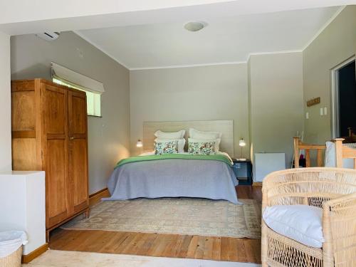 1 dormitorio con 1 cama grande y 1 silla en Eight on Tuin en Franschhoek