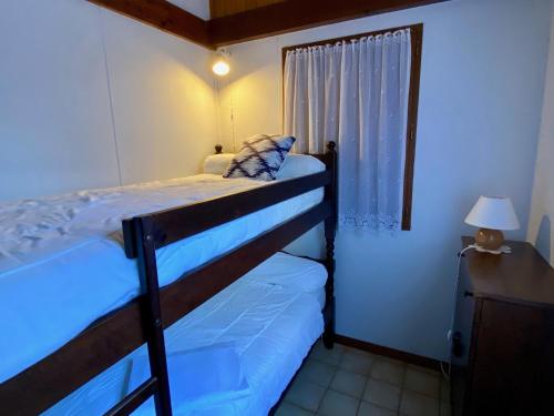 une chambre avec un lit superposé et une fenêtre dans l'établissement Cute chalet very central & close to the beach, à Lacanau