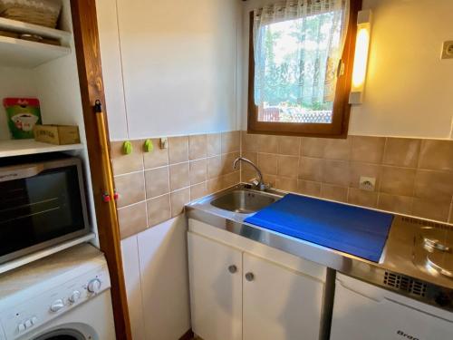 une petite cuisine avec un évier et un micro-ondes dans l'établissement Cute chalet very central & close to the beach, à Lacanau