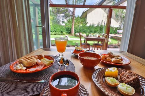 una mesa con platos de comida y un vaso de zumo de naranja en Pousada Serra Paradiso, en Gramado