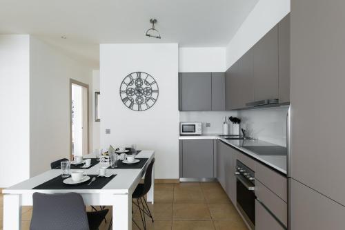 a white kitchen with a table and a counter top at Prestige Apartments by Quokka 360 - spacious flats with terraces in Lugano