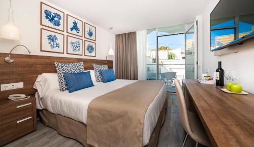 a bedroom with a large bed and a dining room at Globales Don Pedro - Adults Only in Cala de Sant Vicent