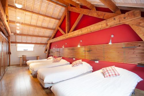 vier bedden in een kamer met rode muren en houten plafonds bij L'Atelier du Moulin d'en Bas in Saint-Hubert
