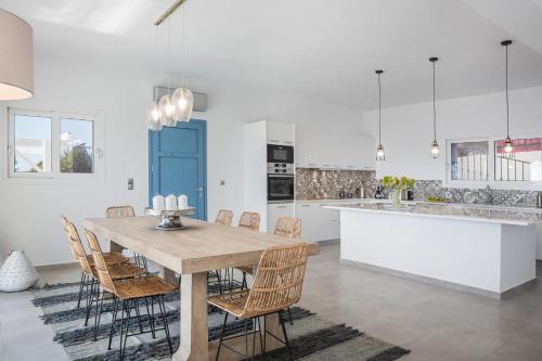 a white kitchen with a wooden table and chairs at Villa Apollonia in Fiskardho