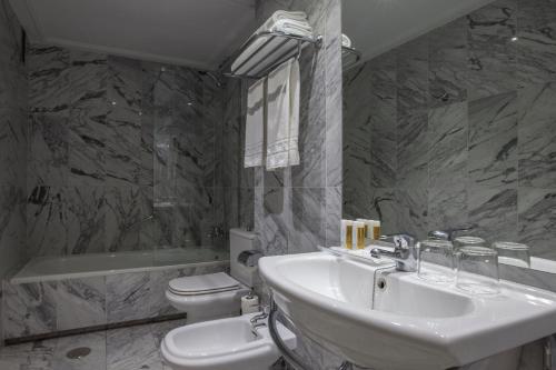 La salle de bains est pourvue d'un lavabo, de toilettes et d'une baignoire. dans l'établissement Porcel Torre Garden, à Madrid