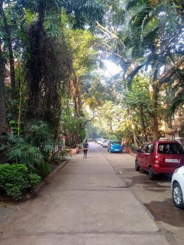 a person walking down a street with trees and cars at Hostel Lifespace- Tailor made for working professionals- Luxurious Twin Bungalow with CoWork- only 3 and 4 share Rooms in Pune