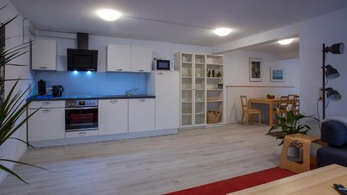 a kitchen with white cabinets and a living room at Im Reuter FEWO2 in Sinsheim