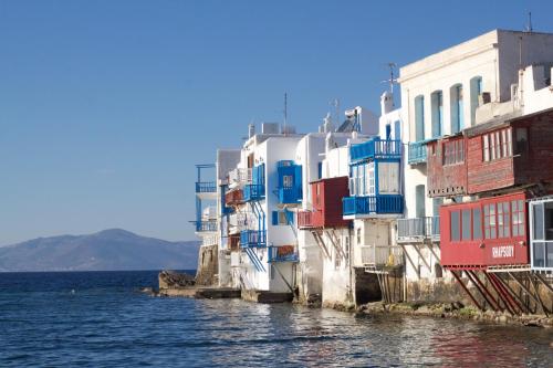 um grupo de edifícios ao lado de uma massa de água em Vista Infinita em Agios Ioannis