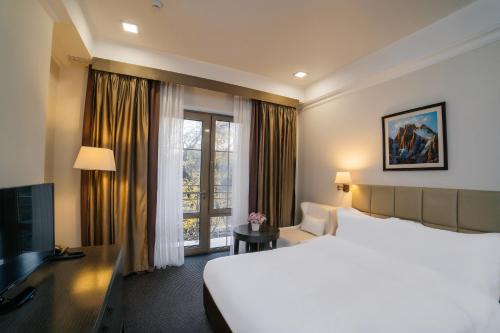 a hotel room with a large bed and a large window at Ambassador Hotel in Bishkek