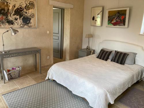 a bedroom with a white bed and a table at Les Lebes - La petite maison in Sempesserre