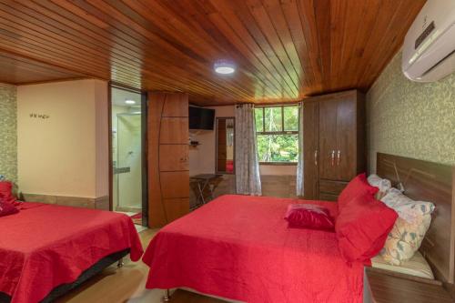 a bedroom with two beds and a red blanket at Pousada Cascata dos Amores in Teresópolis